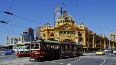 Der Eingang des Hauptbahnhofs Flinders Street Station in Melbourne mit Straßenbahn.